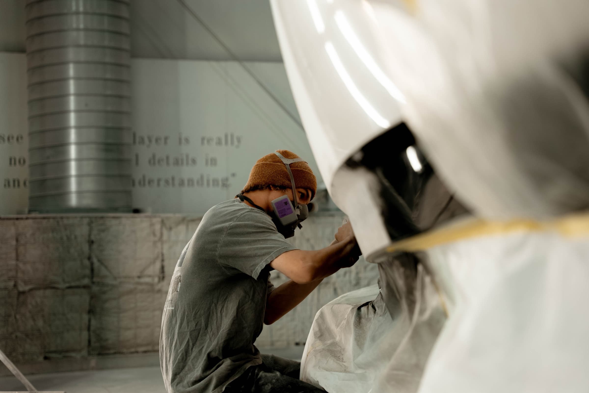 Technician spraying fresh gel coat on a boat hull at Utah Fiberglass Specialties